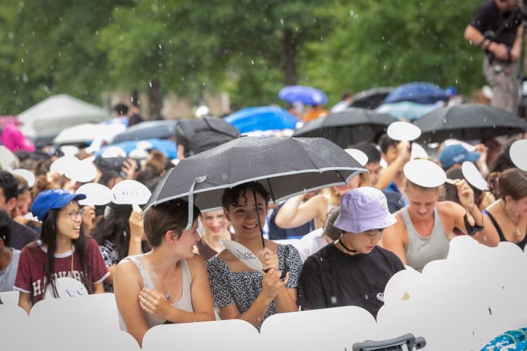 Students take cover in the rain during Sunday’s undergraduate convocation.