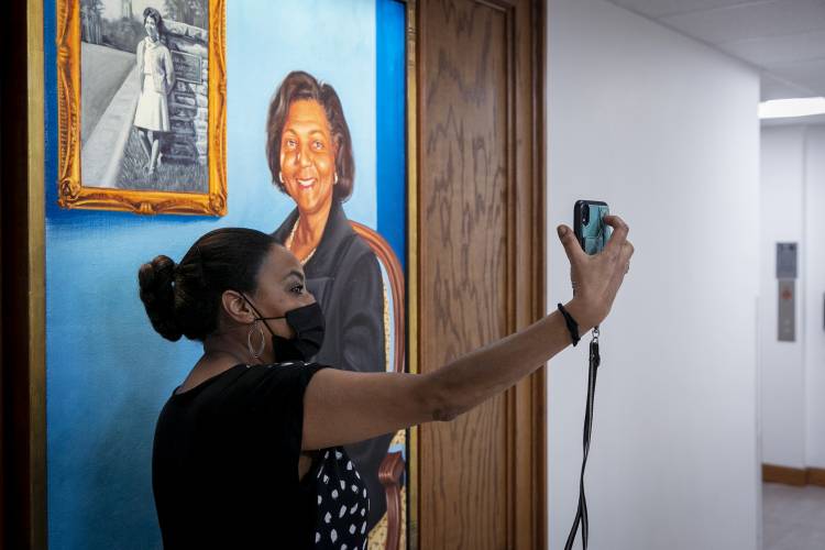 Rahel Ephren, a family friend of the late Wilhelmina Reuben-Cooke, poses for a selfie beside the painting of the late Wilhelmina Reuben-Cooke in the newly dedicated Reuben-Cooke Building