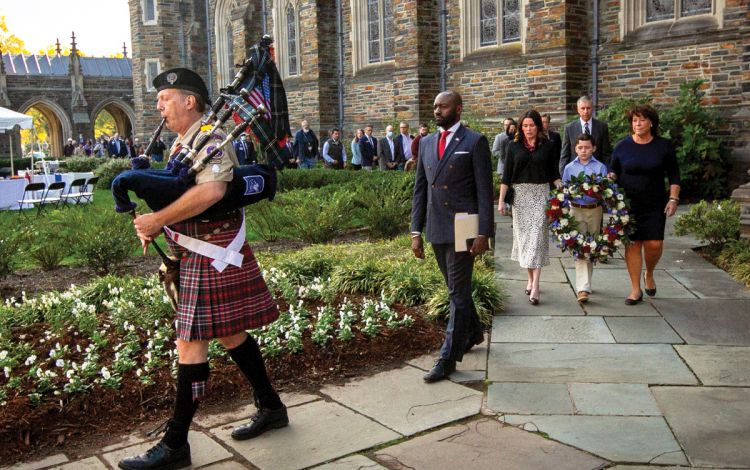Antwan Lofton, second from right, leads a crowd to the wreath laying ceremony outside of Duke University Chapel at the conclusion of the 2021 Veterans Day ceremony. Photo by Stephen Schramm.