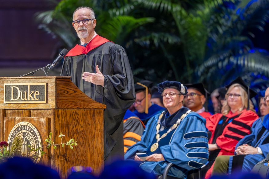 Christoph Guttentag, dean of admissions, standing at a podium with president price and other Duke faculty and administration sitting in the background