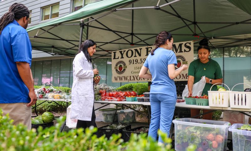 People line up to buy fresh vegetables from Lyon Farms at Duke Farmers Market