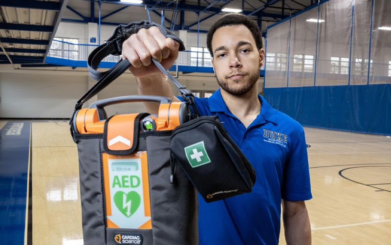 A Wilson Recreation Center employee holds an AED on a basketball court