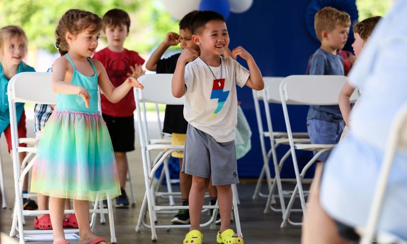 5-year-old kids stand and flex their arms during a performance