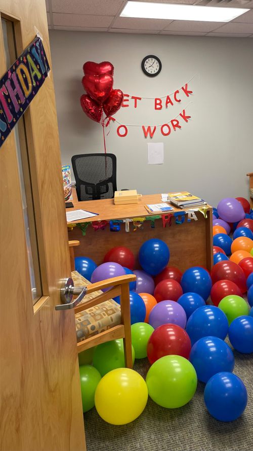 Balloons cover the office floor of a physical therapist who suffered sudden cardiac arrest to welcome him back to work.