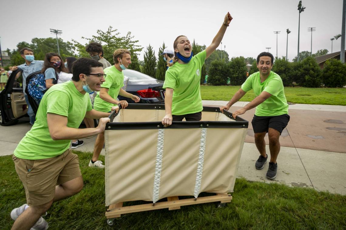 First-Year Advisory Counselors arrive to help on move in day 2021 in a cart.