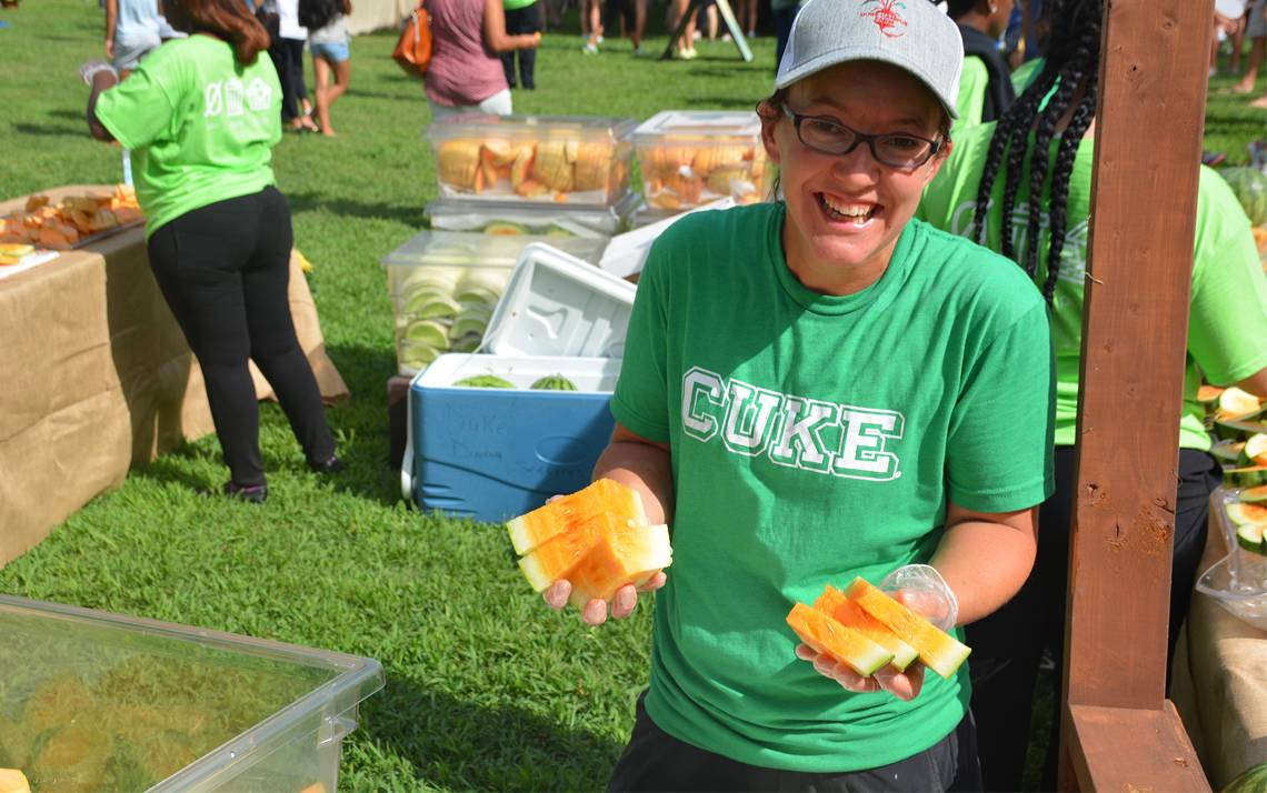While rocking a shirt with the abbreviation for “cucumbers,” Emily McGinty serves Duke Campus Farm's famous Orangeglo watermelons at Duke's First-Year Zero Waste Picnic in August. Photo by Jonathan Black.
