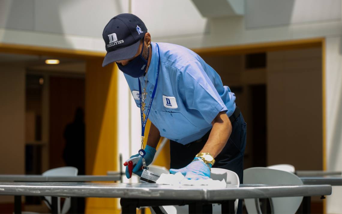 James White, a housekeeper, sweeps floors and sanitizes high touch surfaces such as table tops and chairs at the Fuqua School of Business.