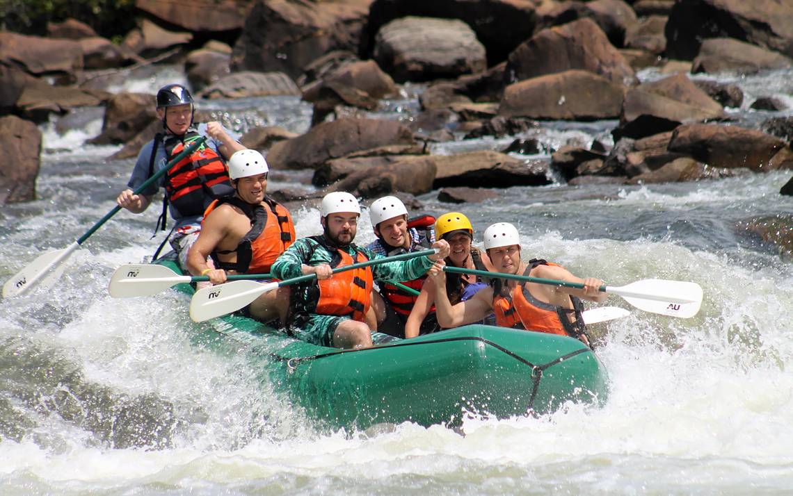 Michael Barnes, at left, helps guide a raft full of friends through rapids during a recent trip.
