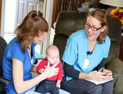 Durham Connects nurse Liz Stevens (right) visits with a new mother and her baby.  Credit: Kara Bonneau