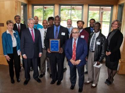 Marvin Tillman, manager of the Library Service Center Team, holds the Teamwork Award plaque won by the Library Service Center team. The team is joined here by President Richard H. Brodhead to Tillman's right and Provost Peter Lange on his left. Photo by 