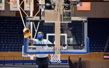Associate Director of Athletics Facilities and Projects Jamal White wipes down the backboard prior to the Duke Women's Basketball team's showdown with South Carolina. Photo by Stephen Schramm.