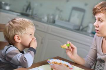 mother tries to feed fussy toddler