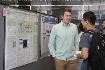 Clayton Connor answers questions about his REU Grand Challenges project at a poster session held in Fitzpatrick Center