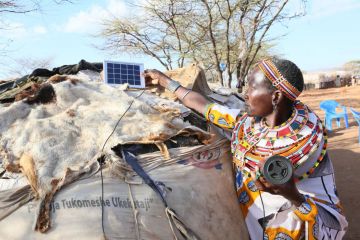 Winning photo from Africa image contest shows Katelina Lekanta, a pastoralist from Samburu in northern Kenya, connects her bluetooth radio to a solar panel for recharge on top of her manyatta,