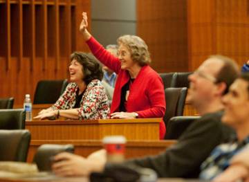Robert Lefkowitz's mother-in-law Charlotte Tippett waves at the image of Lefkowitz entering the Nobel Prize ceremony Monday.  Tippett and others watched the ceremony from a live stream broadcast in Schiciano Auditorium.