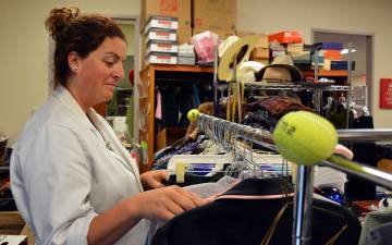 Sarah Walker, a manager at the Nearly New Shoppe, sorts through recently donated shirts and coats. The store, which supports medical and nursing scholarships, is seeking additional donations in the next two weeks.